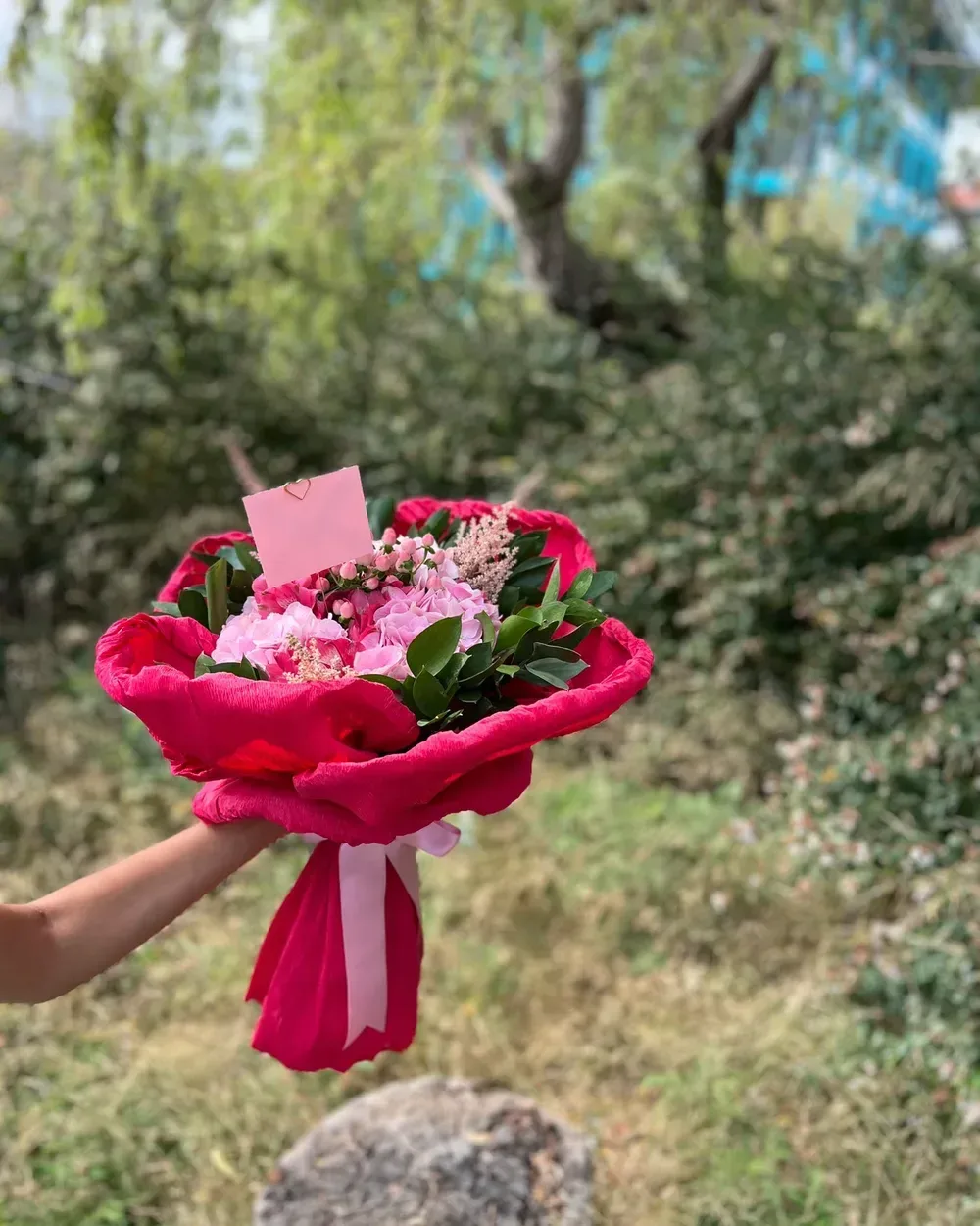 Kırmızı kağıtta pembe ortanca ve astilbe dalları, küçük not kartıyla
